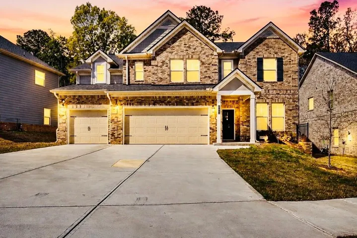 Brick facade residence featuring a covered entry, multiple gabled rooflines, and a three-car garage with carriage-style doors