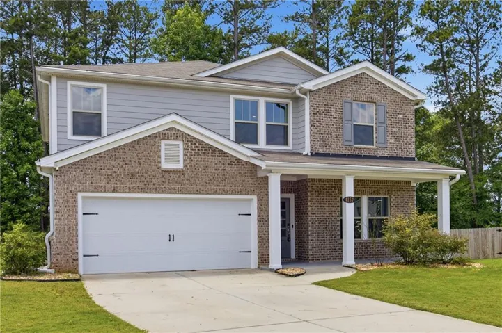 Brick and siding exterior with a covered porch, attached two-car garage, and established landscaping