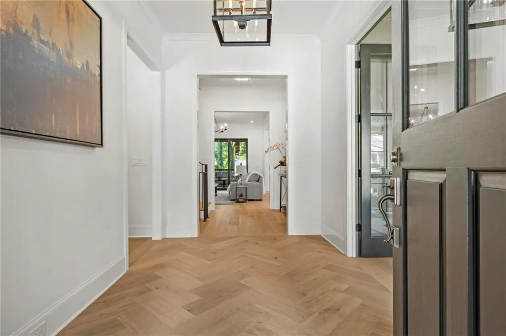 Hallway with ornamental molding and a chandelier, herringbone oak flooring