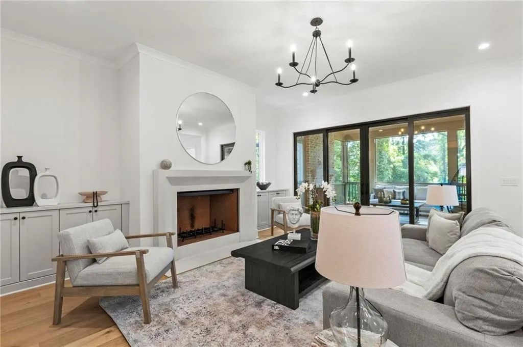 Living room featuring crown molding, light wood-style floors, a chandelier, a fireplace with flush hearth, and recessed lighting