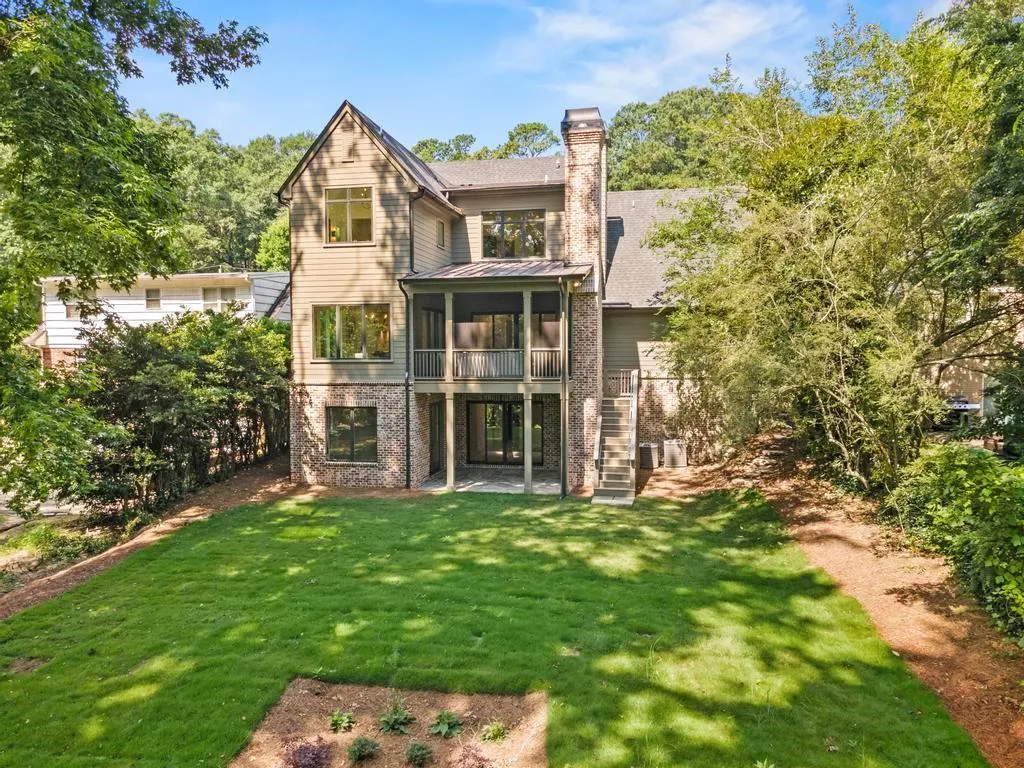 Back of house featuring a chimney, a sunroom, a lawn, stairway, and a patio area