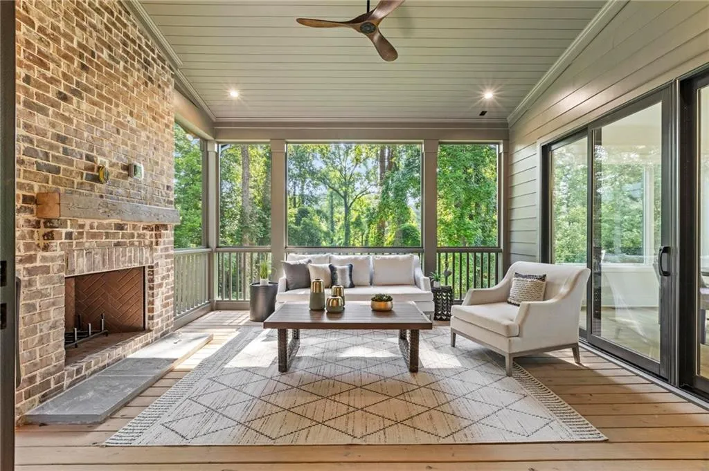 Sunroom featuring ceiling fan, plenty of natural light, and an outdoor living space with a fireplace...literally feels like you are in a treehouse in the woods
