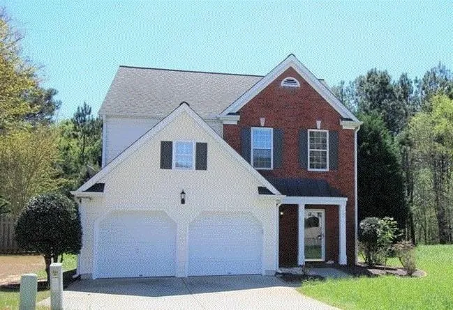 Brick and siding exterior with a two-car garage, covered entry, and traditional shutters