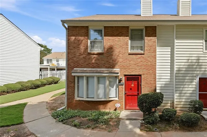 Brick facade featuring a red entry door with white trim