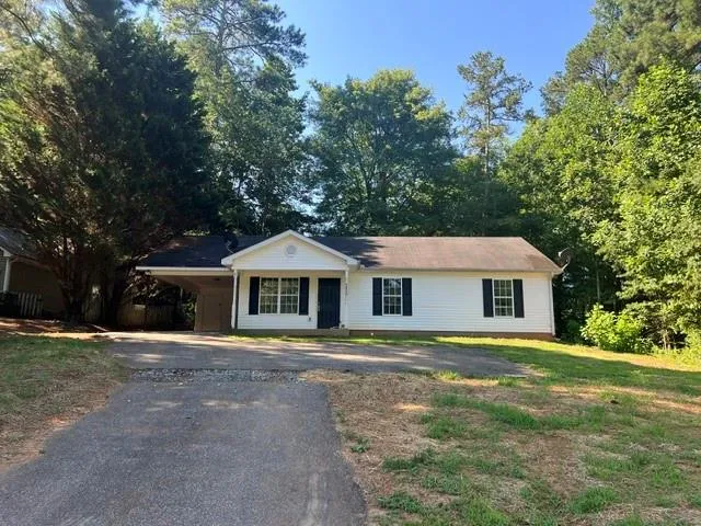 White siding exterior featuring black shutters, a covered carport, and a gabled entry