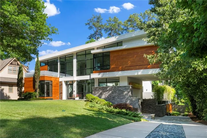 Modern architectural facade featuring extensive glazing, wood-finish siding, and stone accents