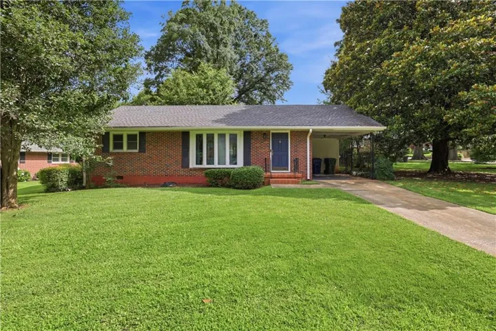 Brick exterior with a dark shingle roof, bay window, and covered carport