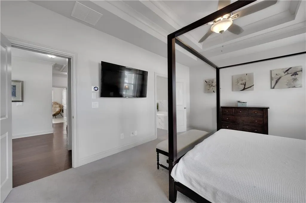 Bedroom with carpet floors, connected bathroom, a ceiling fan, and a raised ceiling
