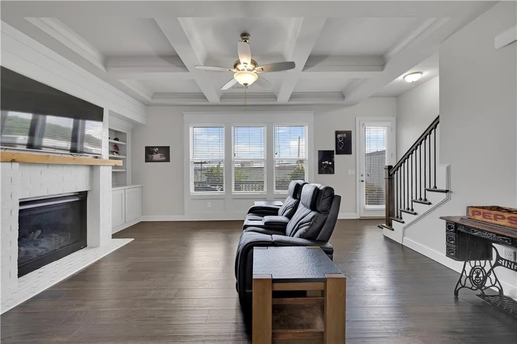 Living area featuring healthy amount of natural light, beamed ceiling, dark wood-type flooring, coffered ceiling, and stairway