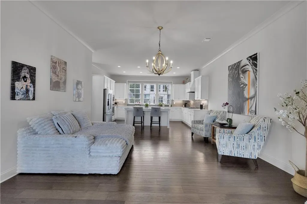 Living area featuring dark wood-type flooring, ornamental molding, recessed lighting, and a chandelier