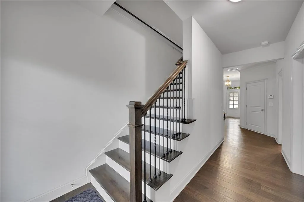 Staircase with wood finished floors and a chandelier