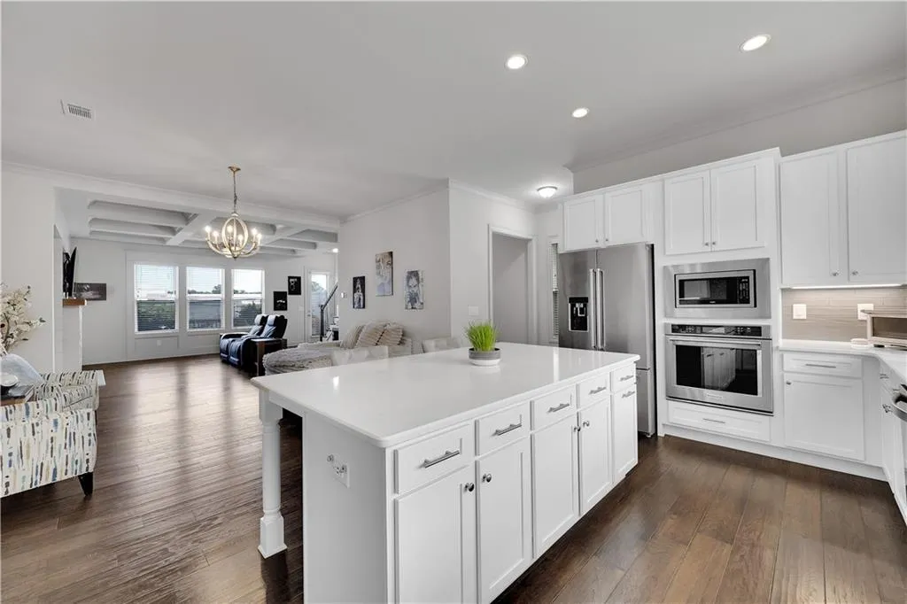Kitchen with white cabinetry, beamed ceiling, stainless steel appliances, coffered ceiling, and a kitchen island