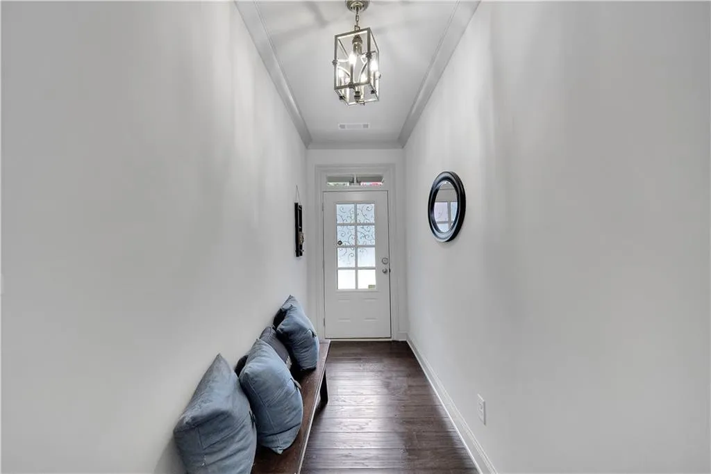 Doorway with ornamental molding, wood finished floors, and a chandelier