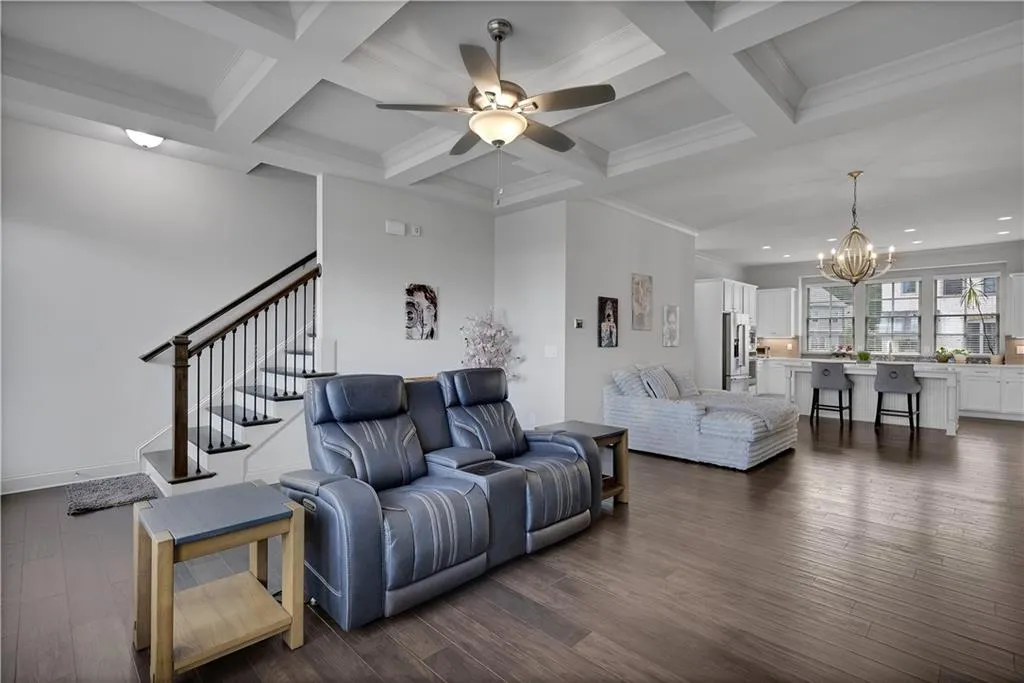 Living room featuring a chandelier, dark wood finished floors, ceiling fan, beamed ceiling, and coffered ceiling