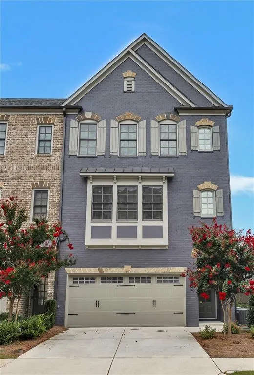French provincial home featuring an attached garage, brick siding, and driveway