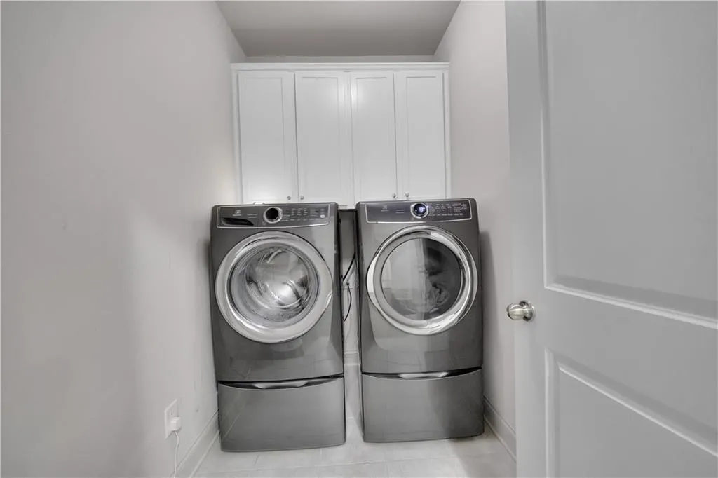 Laundry room with cabinet space, light tile patterned flooring, and independent washer and dryer