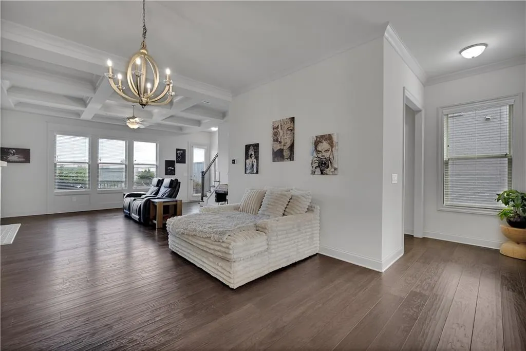 Living room with coffered ceiling, beamed ceiling, dark wood finished floors, healthy amount of natural light, and crown molding