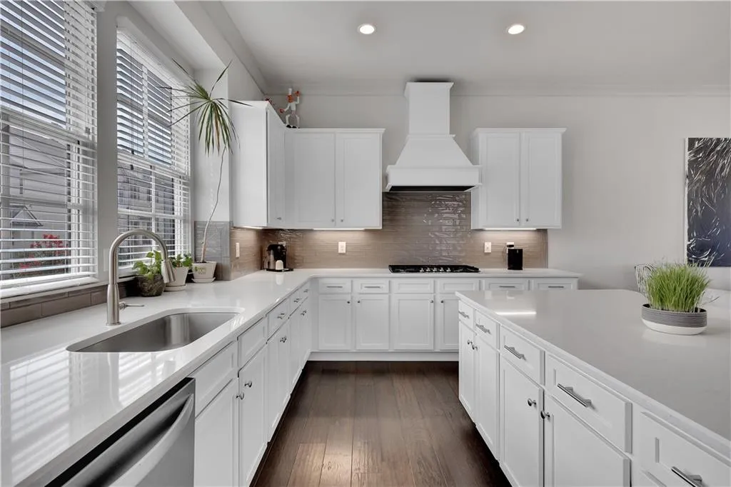 Kitchen featuring white cabinetry, tasteful backsplash, premium range hood, dishwasher, and dark wood-style flooring