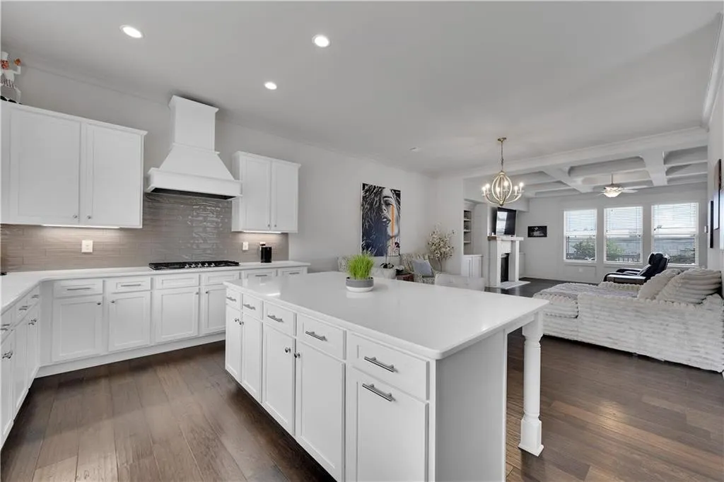 Kitchen featuring coffered ceiling, open floor plan, beam ceiling, white cabinetry, and hanging light fixtures