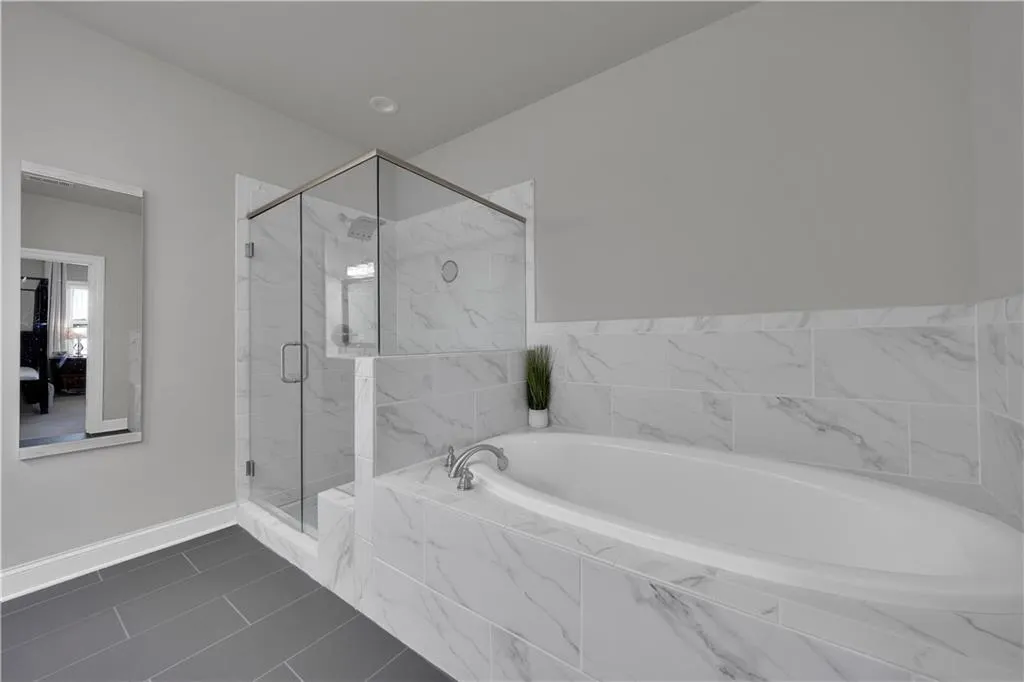Ensuite bathroom with a garden tub, a marble finish shower, and dark tile patterned floors