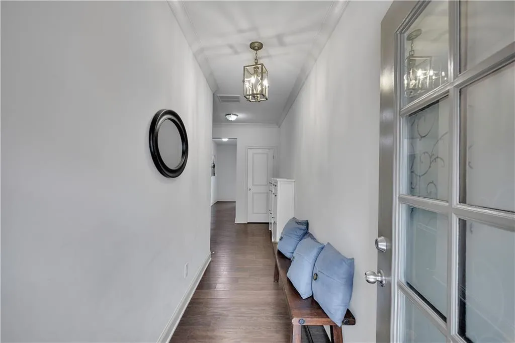 Hallway featuring ornamental molding, dark wood-style flooring, and a chandelier