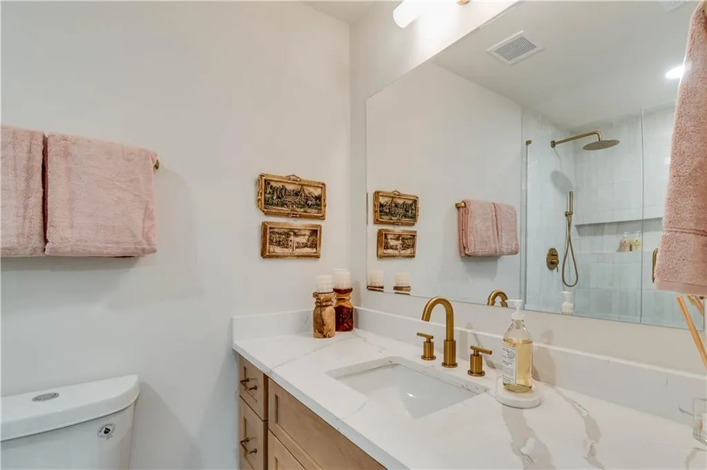 Bathroom with a tile shower, toilet, and large vanity