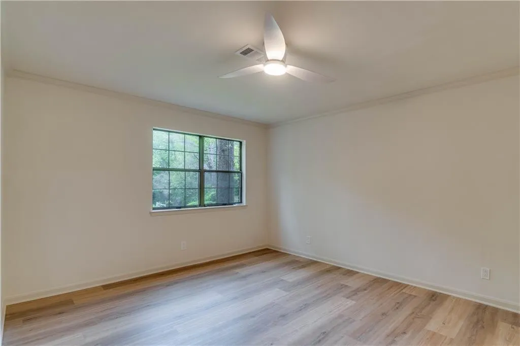 Unfurnished room with ceiling fan, light wood-type flooring, and ornamental molding