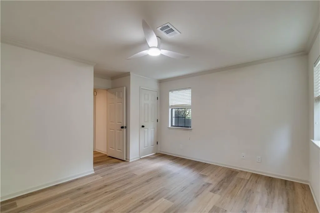 Spare room with crown molding, ceiling fan, and light wood-type flooring