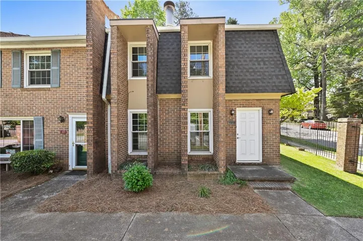 The property features a brick exterior with a dark shingle roof and white entry door