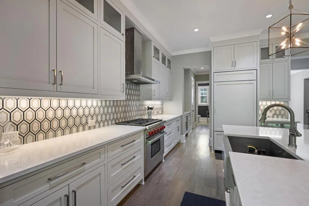 Kitchen featuring glass fronted cabinets, premium appliances, dark wood-type flooring, light stone countertops, and crown molding