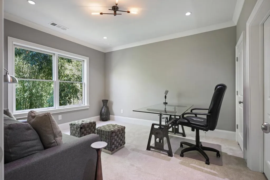 Office area with crown molding, hanging lights, and light carpet