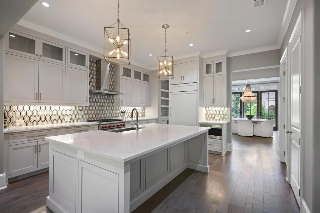 Kitchen featuring glass insert cabinets, tasteful backsplash, a large island, light stone countertops, and dark wood-type flooring