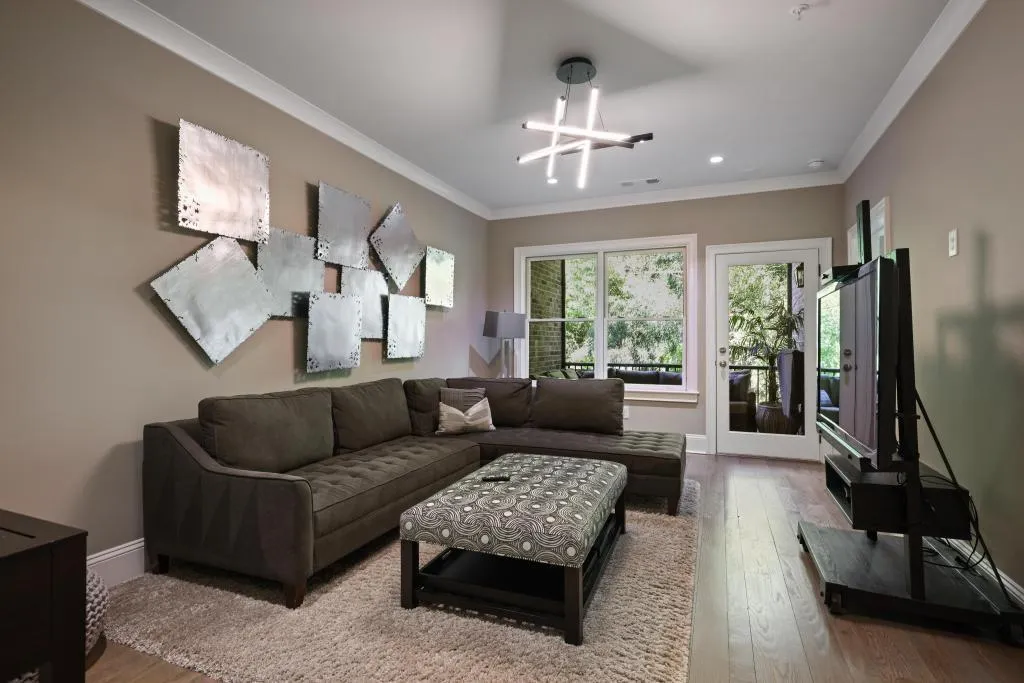 Living room with wood-type flooring, crown molding, and suspended lighting