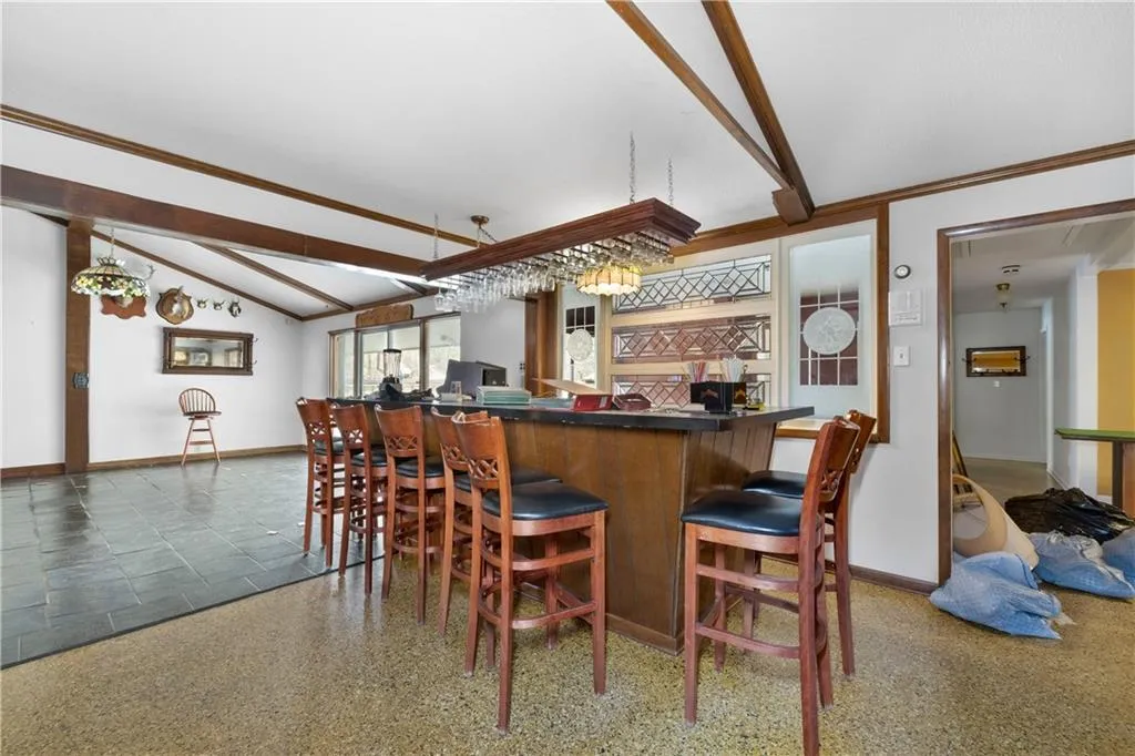 Indoor dry bar with dark countertops, ornamental molding, and light speckled floor