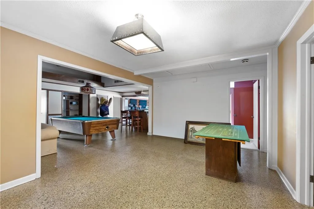 Playroom with billiards table, dark speckled floor, and crown molding
