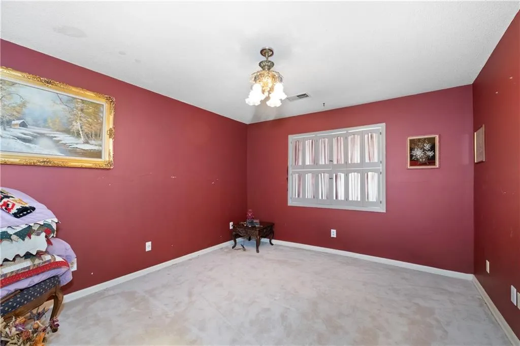 Carpeted spare room with a chandelier and baseboards