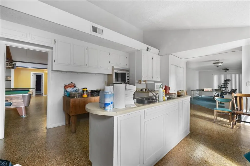 Kitchen with white cabinetry, light countertops, vaulted ceiling, billiards table, and open floor plan