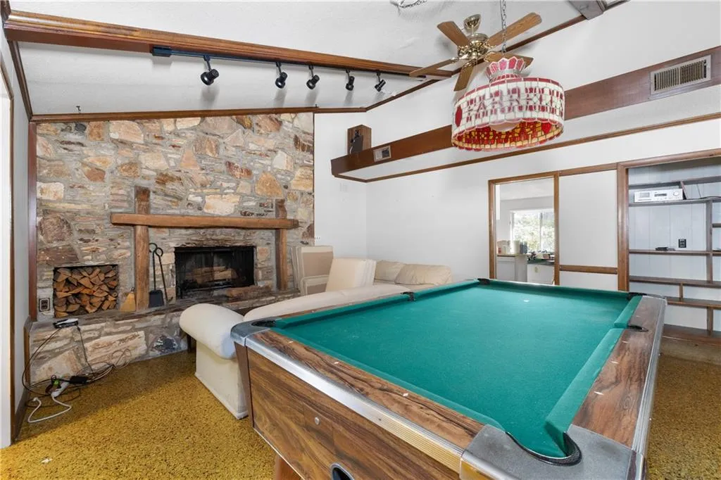 Game room featuring pool table, a stone fireplace, speckle patterned floor, ceiling fan, and high vaulted ceiling