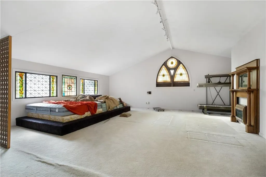 Carpeted living room with rail lighting and vaulted ceiling