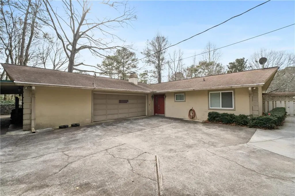 View of side of property with stucco siding, concrete driveway, a chimney, and roof with shingles