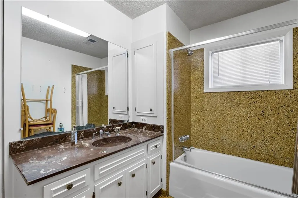 Bathroom with a textured ceiling, vanity, and  shower combination