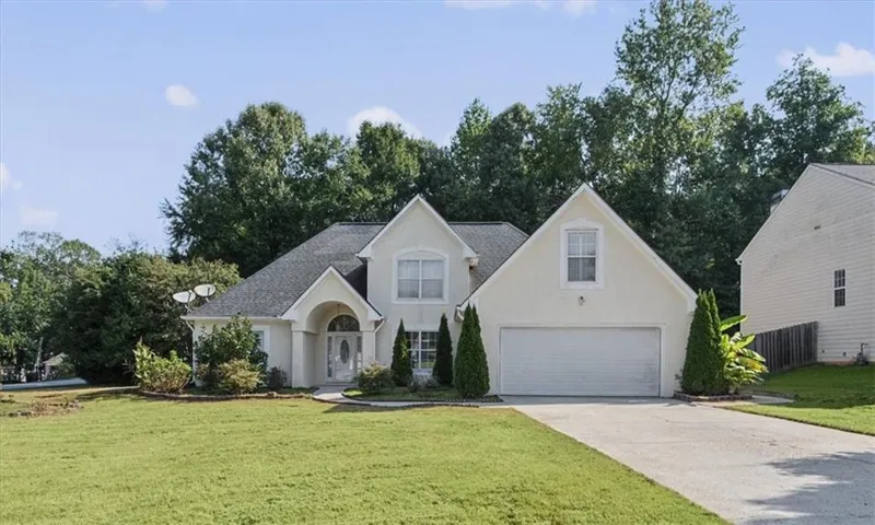Stucco exterior with an arched entry, two-car garage, and landscaped front yard