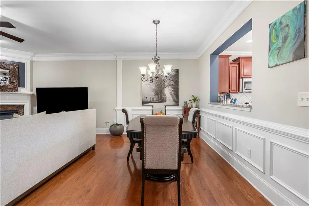 Dining room featuring ornamental molding, dark wood finished floors, a fireplace, a chandelier, and a decorative wall