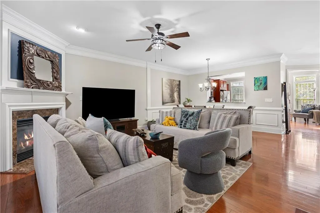 Living room with ornamental molding, hardwood / wood-style floors, a ceiling fan, a chandelier, and a premium fireplace