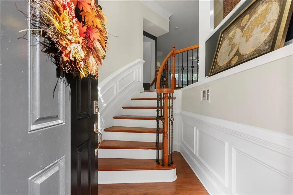 Stairs featuring a decorative wall, wood finished floors, and a wainscoted wall