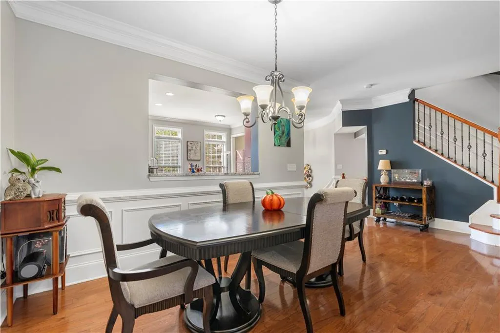 Dining room with stairway, ornamental molding, light wood-style floors, a chandelier, and a decorative wall