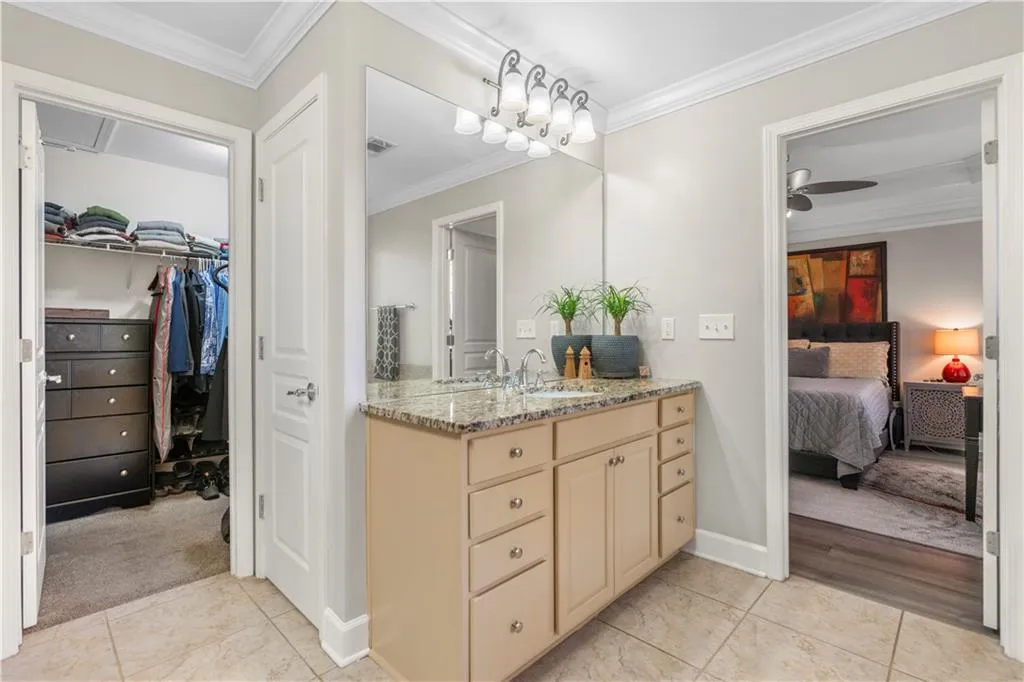 Bathroom with crown molding, ensuite bathroom, vanity, light tile patterned flooring, and a ceiling fan