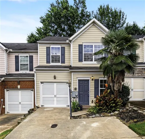 Two-story townhouse exterior featuring a neutral-toned siding facade with dark blue shutters