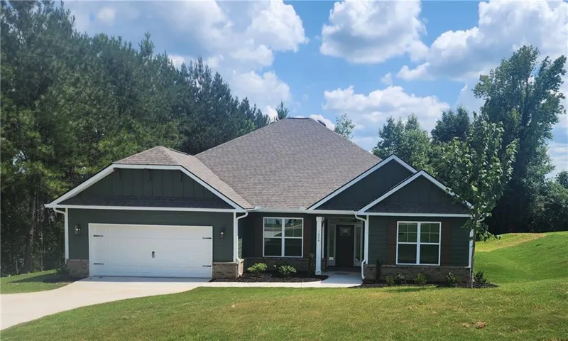 Dark green siding, white trim, and a stone accent foundation