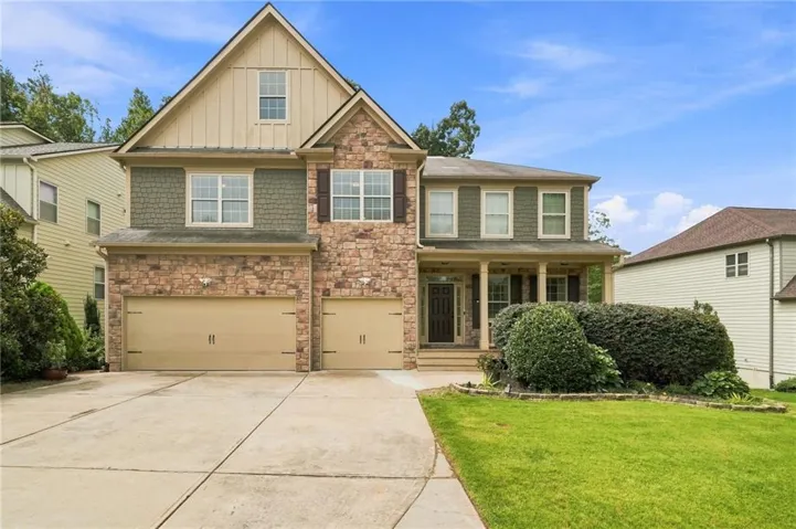 The thoughtfully designed façade is complemented by a welcoming covered front porch, elegant architectural detail blending shaker-style siding, rich stone accents, multiple rooflines, and dramatic gabled peaks